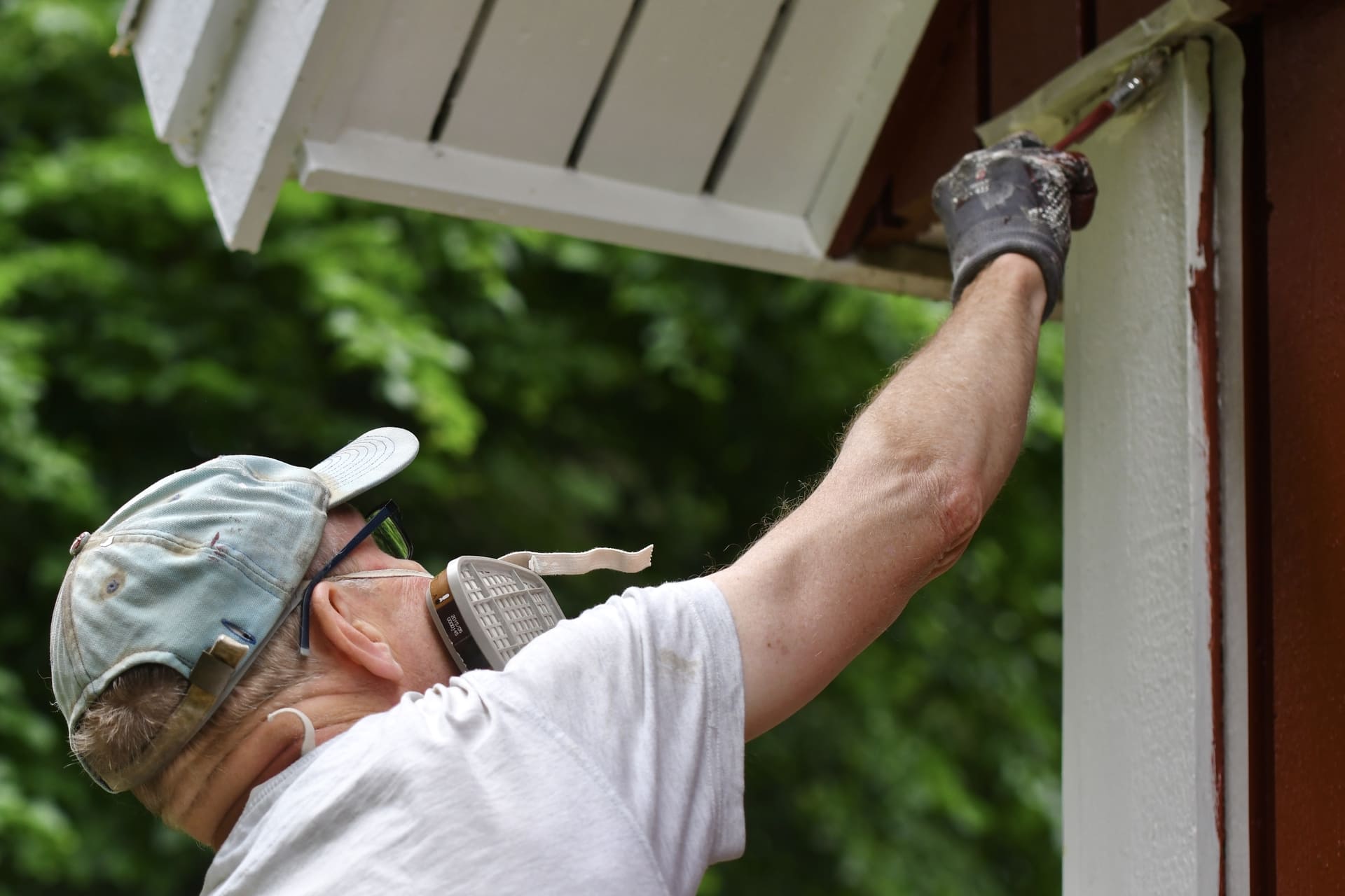 man-wearing-protective-mask-painting-house-exterior-with-white-paint