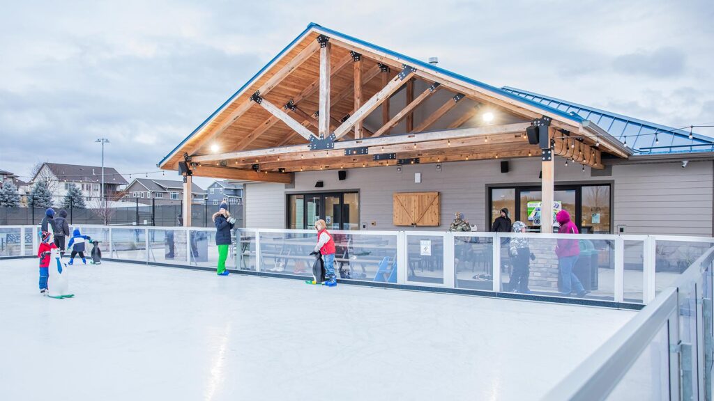 Outdoor ice skating rink with community pavilion and skaters in winter attire