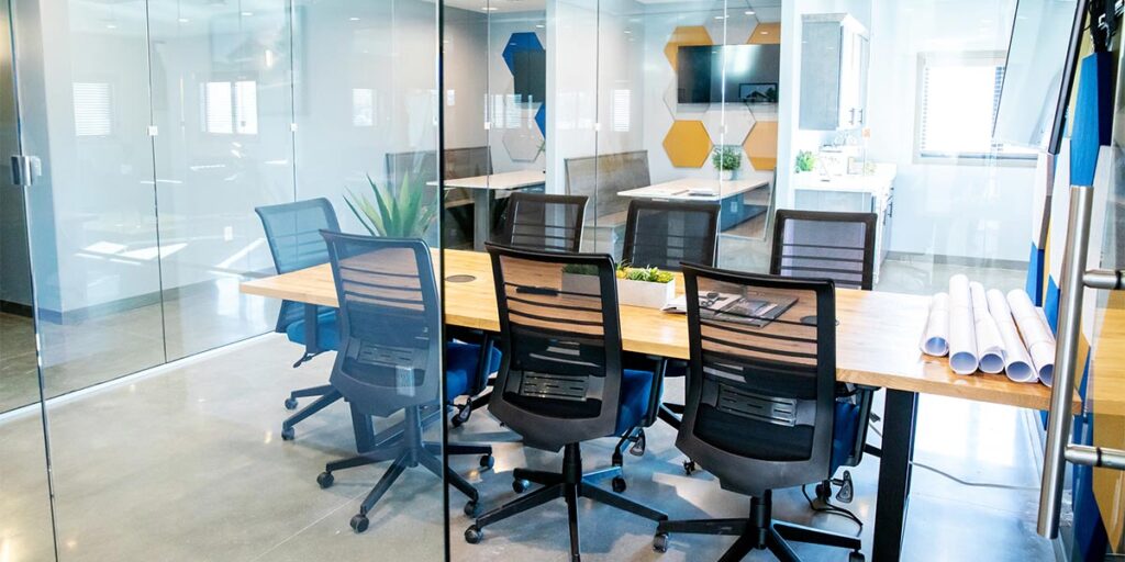 Modern glass-walled conference room with collaborative workspace and meeting table