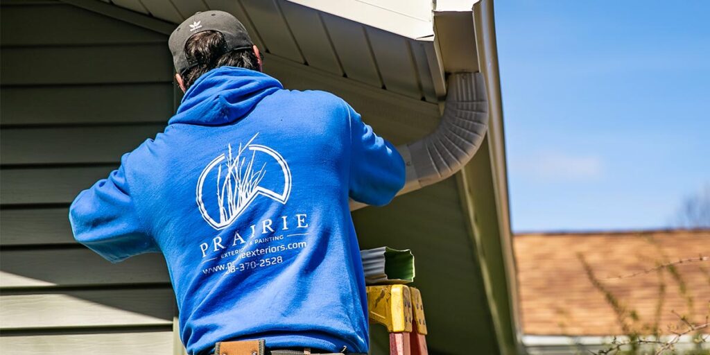 Prairie Exteriors technician inspecting and servicing residential gutter system